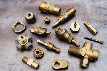 Obraz na płótnie Canvas Brass scrap metal: taps, tees, plugs and various plumbing parts, spare parts. Against the background of a copper sheet. Close-up.