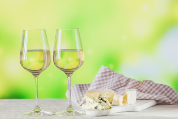 White wine served with cheese plate on light green background. Two wineglasses of vino verde. Seasonal holidays concept