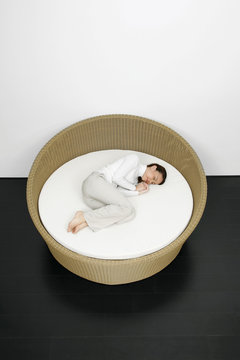 Woman Curled Up In A Rattan Bed