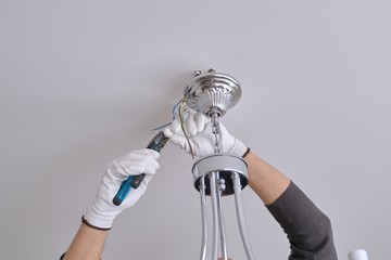 Installation ceiling lamp, hands of electrician fixing chandelier