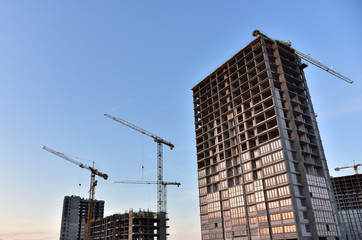 Fototapeta na wymiar Construction of a new multi-storey building. The facade building with windows and balconies. Tower crane working at construction site. Modern residential building architecture background