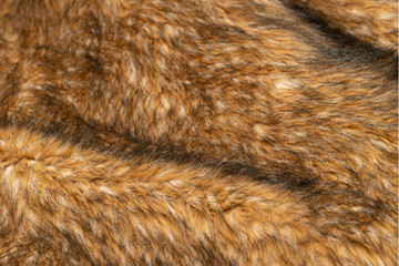Close-up of a fluffy dark brown faux fur fabric with a background texture.