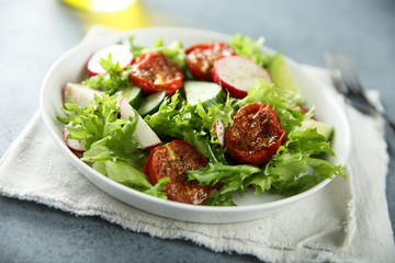 Healthy green salad with sun dried tomatoes, radish, cucumber
