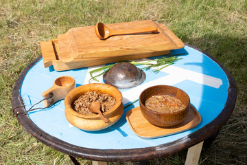 Groats porridge, onions and natural food in wooden dishes on a medieval round shield used as a table in a campaign