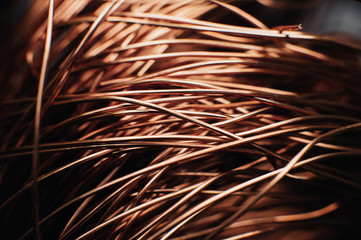 Fototapeta premium Copper scrap metal, wire, windings of motors and transformers, electrical wire without insulation. Against the background of a copper sheet. Close-up. Macro.