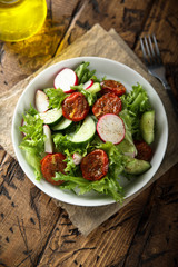 Healthy green salad with sun dried tomatoes, radish, cucumber