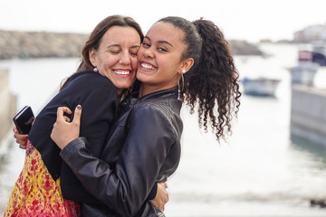 Love of caucasian mother and latin daughter. Happy women in a nice day with on blurred background. Aged woman and her adult daughter near of the sea. Family and mother's day concept - Image
