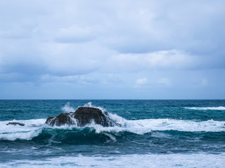 ocean waves hit the rocks. sea foam and cloudy sky