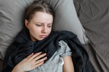 woman is sick at home on the bed. Pain in chest. Coronavirus (COVID-19) Symptoms of a coronary virus infection include shortness of breath, chest pain. For some people, it can lead to pneumon