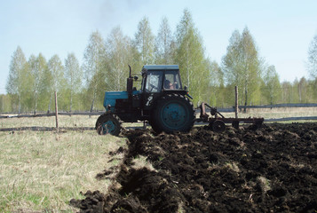 Fototapeta premium Tractor cultivates field in spring. Land cultivation.