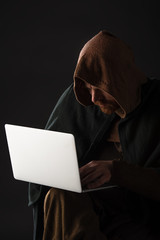 medieval Scottish man in mantel using laptop in dark isolated on black