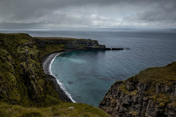 Landscape off the island of Grimsey in the north of Iceland beyond the Arctic Circle. The ocean is an icy clear blue, the sky a little cloudy and many rocks on below the cliffs