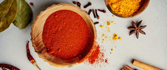 Various colorful spices in wood bowls on concrete background. Top view with copy space. Different Pepper, turmeric, paprika, rosemary, chilly, cardamom, cinnamon, anise, cloves.