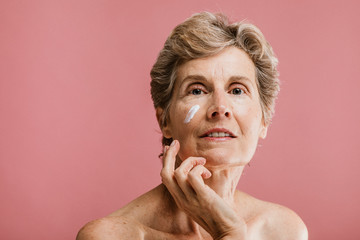 Senior woman using facial cream