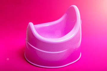 Pink potty and toilet paper on the purple floor. Toilet training chamber pot for small children.