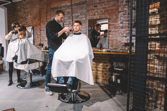 Hairdressers cut their clients in barbershop. Advertising and barber shop concept