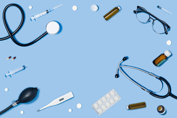 Medical blue background with different accessories: stethoscope, syringe and tablets.