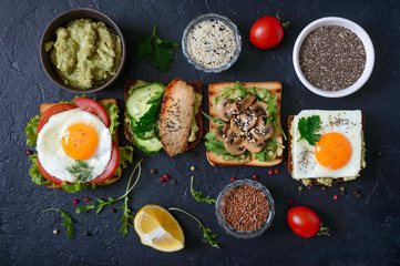 Different sandwiches on a black background. Tasty healthy appetizer with avocado. Quick breakfasts. Healthy eating concept. Proper nutrition. Top view.