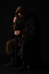 Fototapeta na wymiar medieval Scottish man in mantel with sword in dark isolated on black