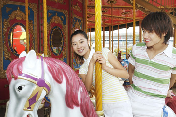 Fototapeta na wymiar Man and woman riding on carousel