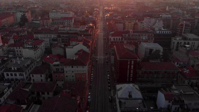 Drone aerial view of Milan skyline from above against colourful sunset over the city. Shot in Lambrate area during Coronavirus lockdown quarantine. Tilting upward and revealing the horizon.