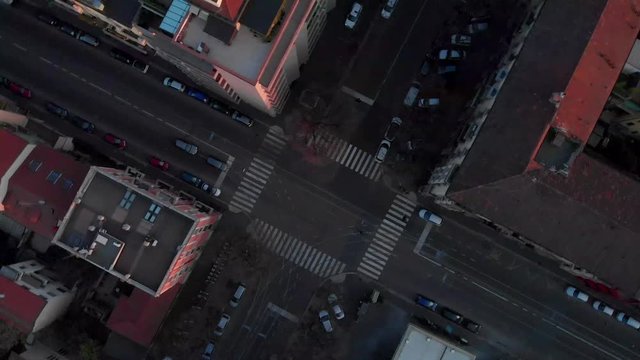 Drone aerial view of Milan from above the city at dusk. Drone looking down at pedestrian crossing and roofs. Shot in Lambrate area during Coronavirus lockdown quarantine. Moving upward and spinning.