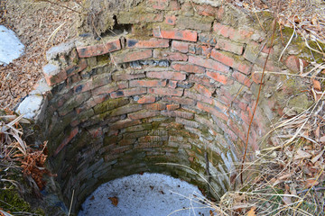 An abandoned old brick well in winter