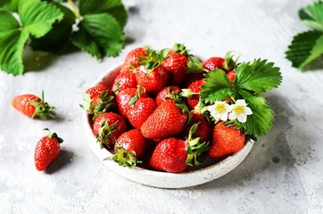 Fresh strawberries in a bowl on a gray background, still life