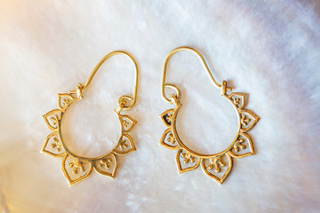 Brass pair of earrings in oriental style on white shell background