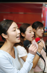 Women singing into microphones