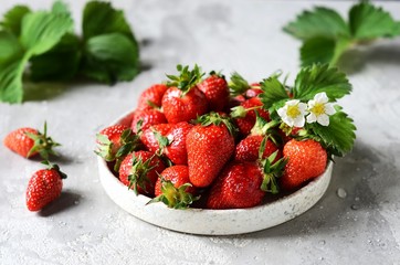 Fresh strawberries in a bowl on a gray background, still life