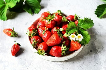 Fresh strawberries in a bowl on a gray background, still life