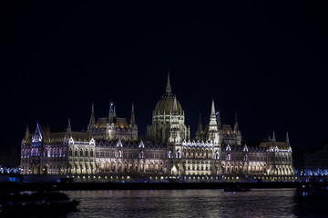Fototapeta premium Beautiful illuminated famous Budapest parliament building along Danube River at night