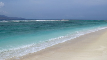 Beautiful blue ocean and tropical sand beach on sunny summer day. Amazing sea view with azure crystal water. Scenic cloudy sky in background.