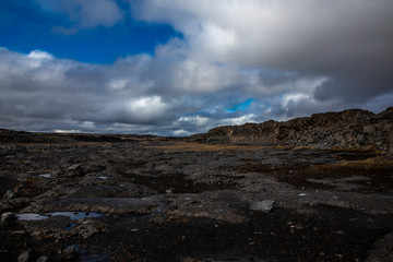 General view of the desert near the Detifoss waterfall in the north of Iceland. The sky is cloudy. The desert is made up of dark volcanic stones covered with greenish moss