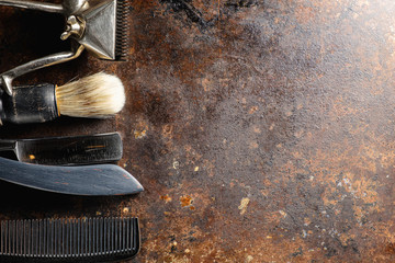 On a rusty surface are old hairdresser tools. manual clipper, comb, razor, shaving brush. rustic. horizontal. top view. flat ley. copy space.