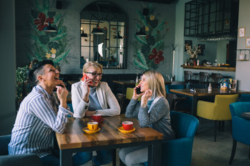 women friends having coffee break at cafe, using mobile phone