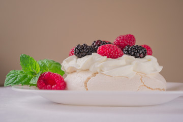 Homemade meringue cake Pavlova with whipped cream, fresh blackberries and raspberries on the top. Dessert background.