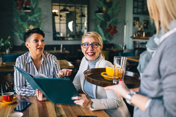 women at restaurant, looking at the food menu,