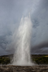 Fototapeta na wymiar Geyser erupting on Geysir geothermal field in central Iceland. A waterspout flies up to the sky for about 30 meters and immediately drops