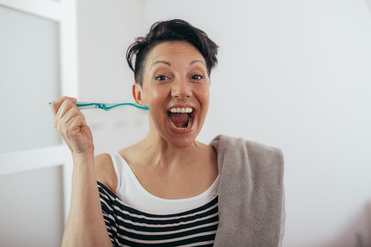 woman holding tooth brush and towel at home