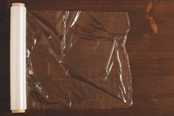 Big roll of transparent packaging film on a wooden background. Top view. Copy, empty space for text