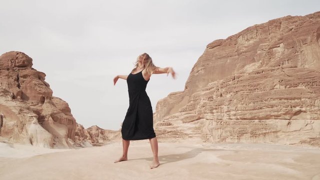 Girl in black suit practice ecstatic dance in desert