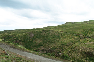 Amazing mountain landscape. Old asphalt road in hilly area near green meadows in cloudy weather