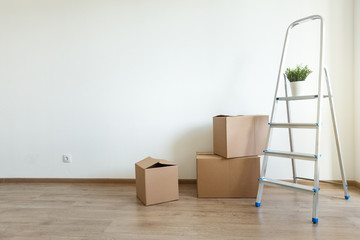 Different cardboard boxes for moving and ladder at empty room © photopixel