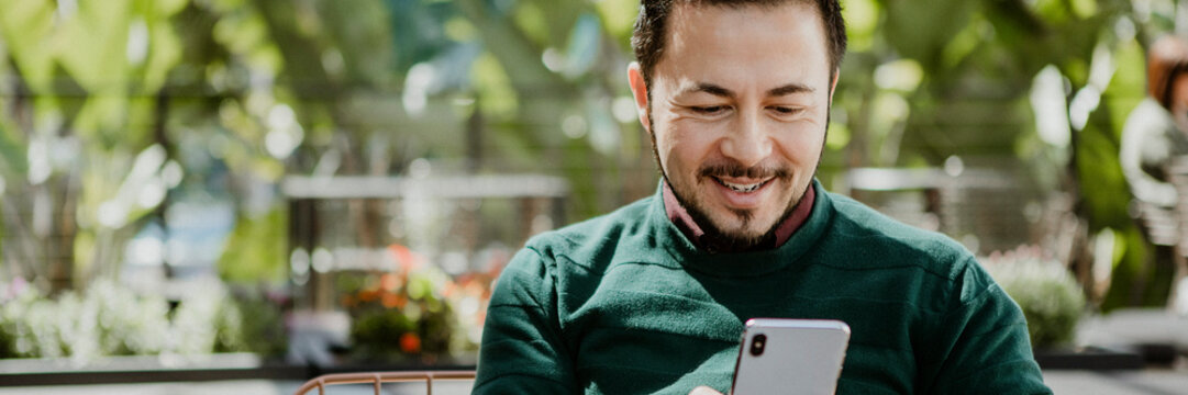 Happy Man Using A Smartphone In A Cafe