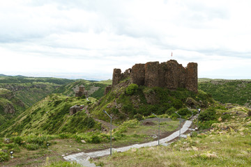 Old castle on top of hill. Picturesque mountain landscape with rocky fortress in cloudy weather