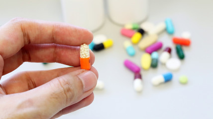 Woman hands holding an orange-white capsule of Theophylline, used in therapy for respiratory disease, treat patients chronic pulmonary disease, asthma. Isolated with colorful drugs, pills and tablet.