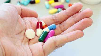 Colorful tablets, pills and capsules medicine in hands use for treatment and cure the disease or sickness. Drug prescription for medication in medical clinic, pharmacy Pharmaceutical service concept.
