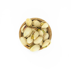 Pistachios in wood bowl close up isolated on white background.